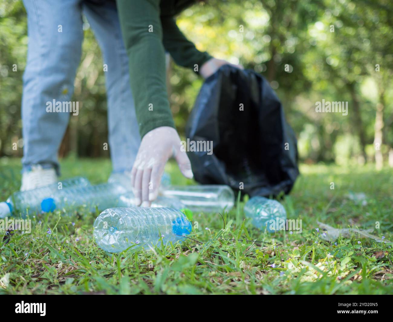 Frauen engagierter Freiwilliger nehmen an einer Umweltreinigungsaktion in einem Park Teil. Frau trägt Handschuhe und hält große schwarze Taschen. Frau Stockfoto
