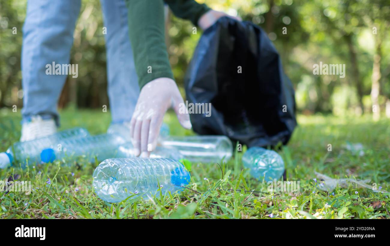 Frauen engagierter Freiwilliger nehmen an einer Umweltreinigungsaktion in einem Park Teil. Frau trägt Handschuhe und hält große schwarze Taschen. Frau Stockfoto