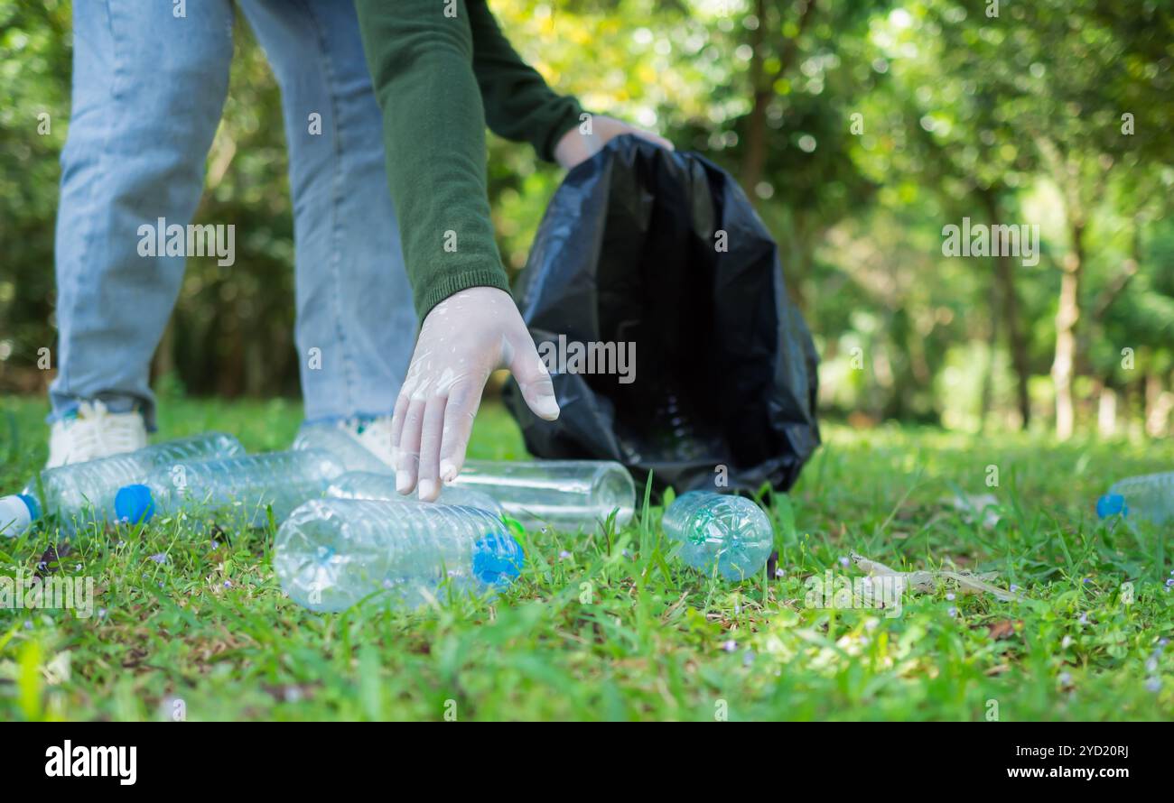 Frauen engagierter Freiwilliger nehmen an einer Umweltreinigungsaktion in einem Park Teil. Frau trägt Handschuhe und hält große schwarze Taschen. Frau Stockfoto