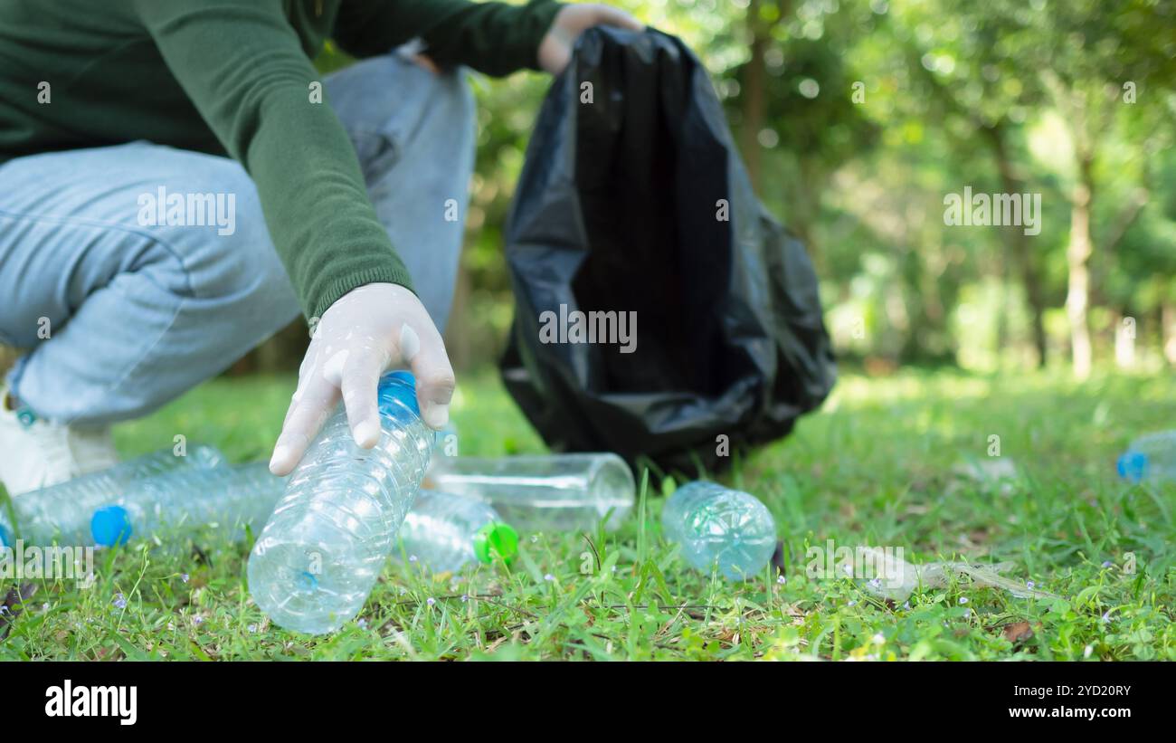 Frauen engagierter Freiwilliger nehmen an einer Umweltreinigungsaktion in einem Park Teil. Frau trägt Handschuhe und hält große schwarze Taschen. Frau Stockfoto