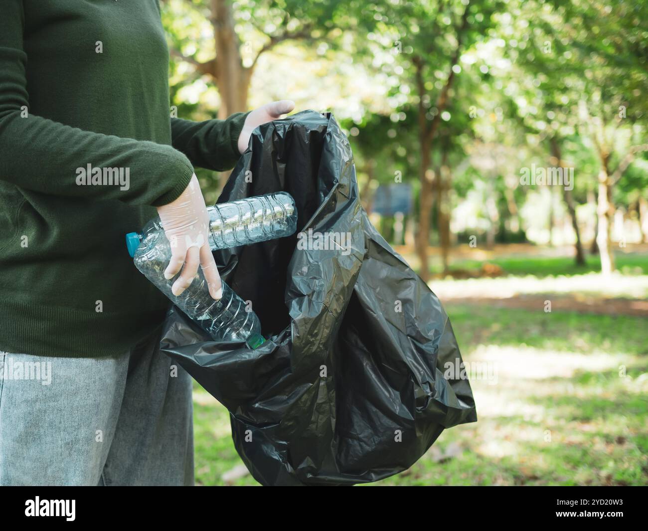 Frauen engagierter Freiwilliger nehmen an einer Umweltreinigungsaktion in einem Park Teil. Frau trägt Handschuhe und hält große schwarze Taschen. Frau Stockfoto