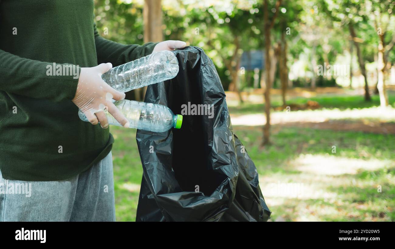 Frauen engagierter Freiwilliger nehmen an einer Umweltreinigungsaktion in einem Park Teil. Frau trägt Handschuhe und hält große schwarze Taschen. Frau Stockfoto