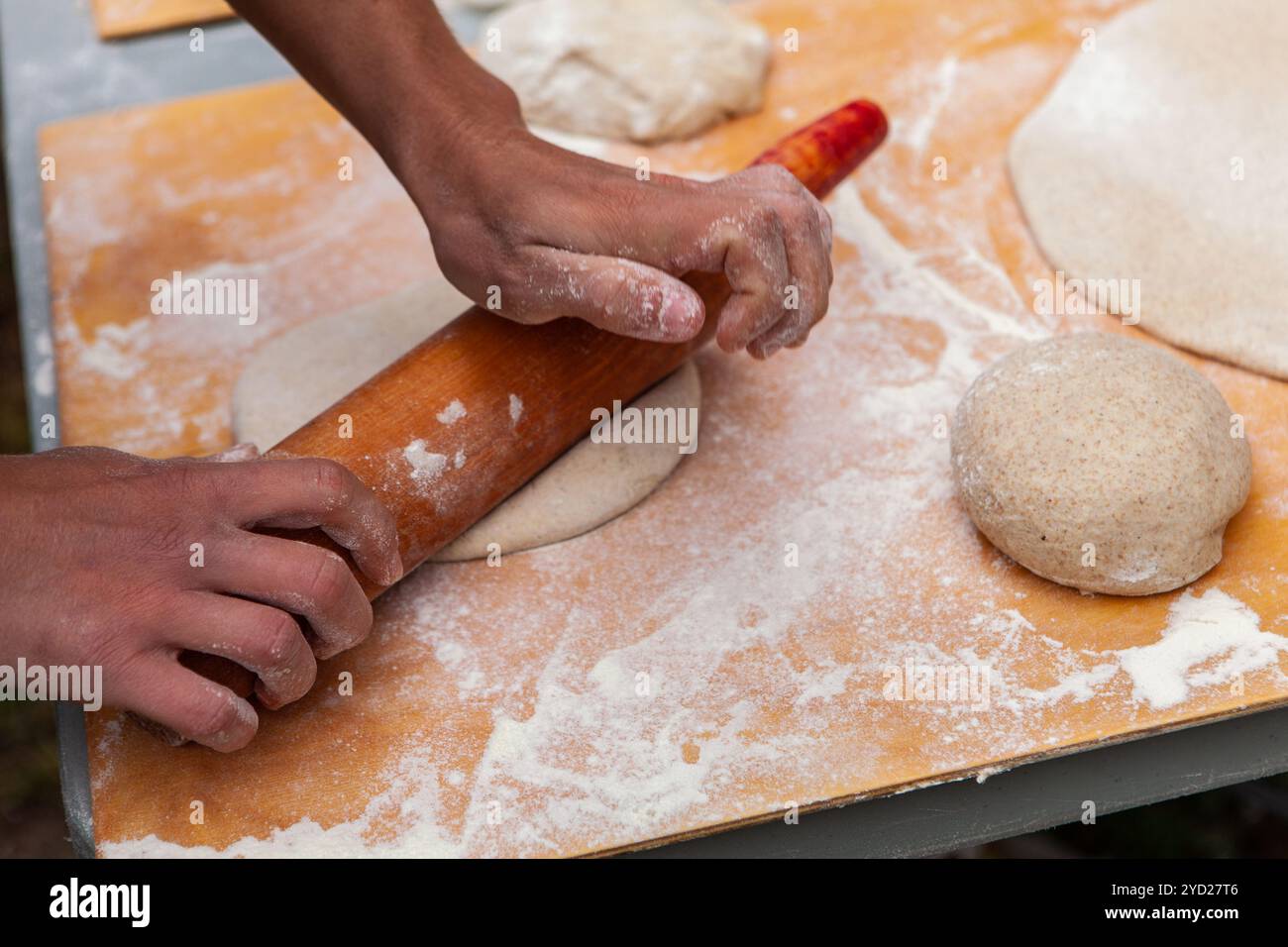 Menschen kneten ihre Pizzateige im Rahmen einer Brotbackwerkstatt im Freien Stockfoto