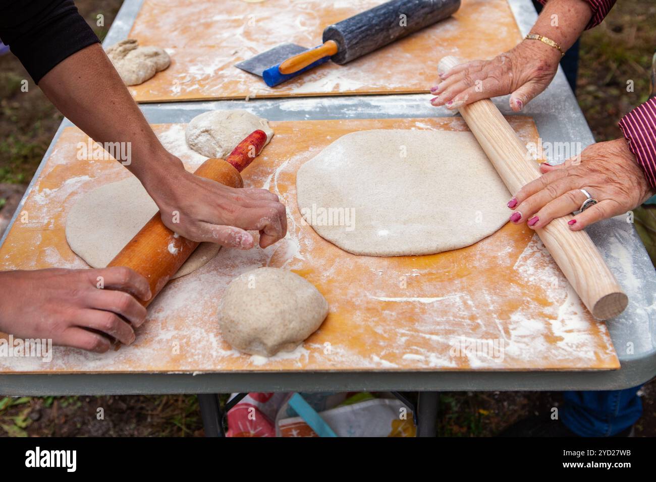 Menschen kneten ihre Pizzateige im Rahmen einer Brotbackwerkstatt im Freien Stockfoto