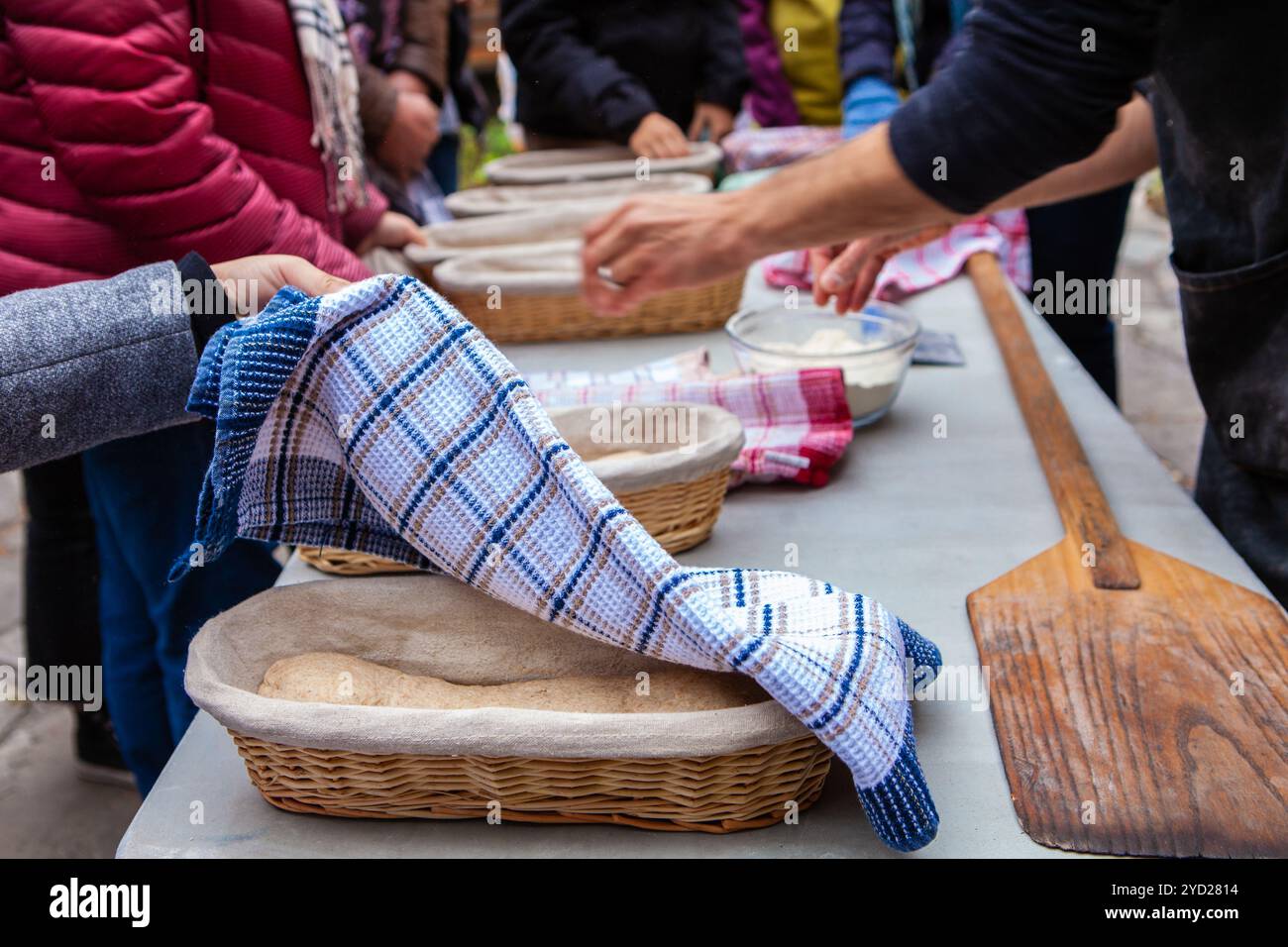 Menschen bewundern ihr Brot, bevor sie in den Brotbackofen gestellt werden Stockfoto