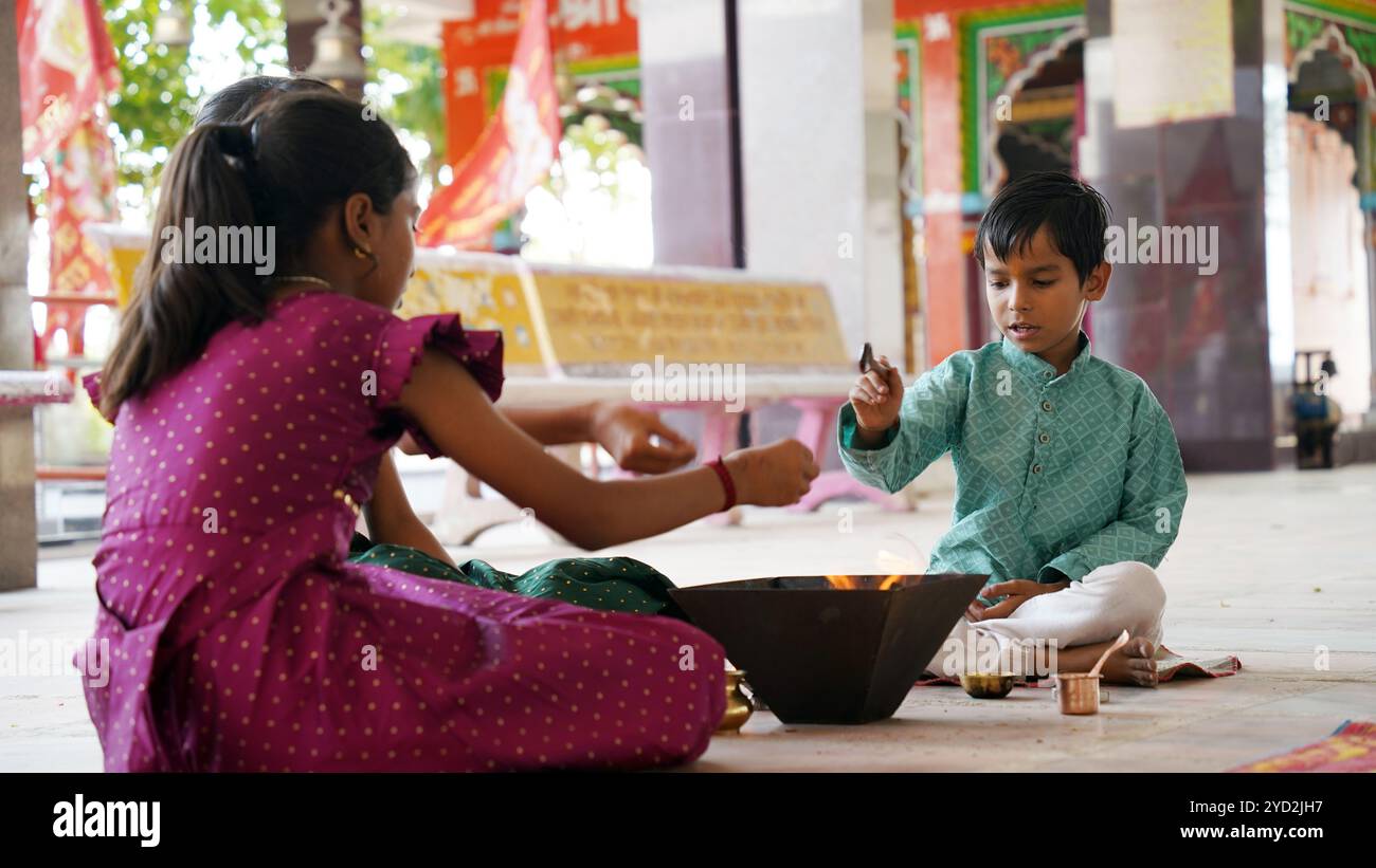Eine indische Familie in traditioneller Kleidung führt eine Yagya oder Havan aus, die von einem Priester geleitet wird, um die Energien in ihrem Haus auszugleichen. Dieser heilige pooja ist für Harmonie Stockfoto