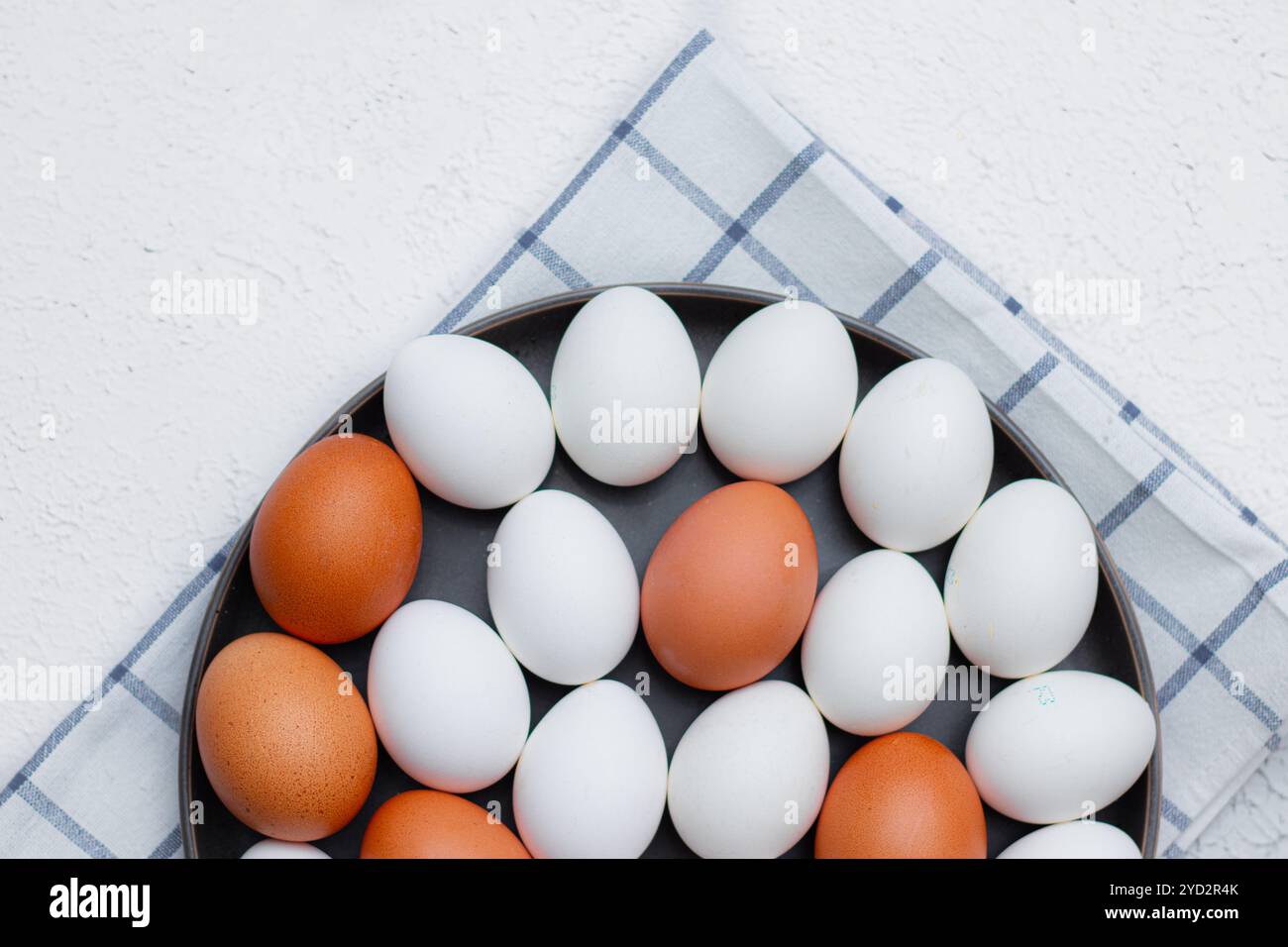 Hühnereier auf einem karierten Küchentuch auf einem Lichttisch. Das Konzept der landwirtschaftlichen Erzeugnisse und der natürlichen Ernährung. Artikel über Haushaltsprodukte Stockfoto