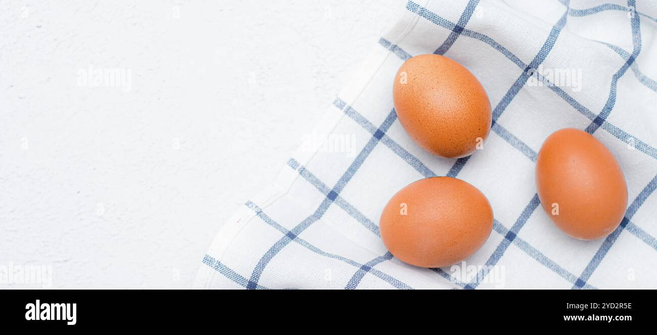 Hühnereier auf einem karierten Küchentuch auf einem Lichttisch. Das Konzept der landwirtschaftlichen Erzeugnisse und der natürlichen Ernährung. Artikel und Anzeigen zu Hause Stockfoto