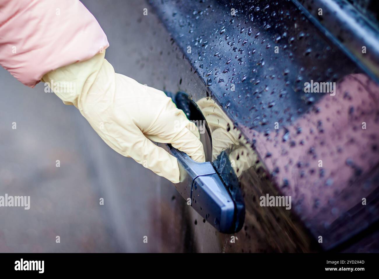 Die Hand einer Frau in einem medizinischen Handschuh öffnet die Autotür. Öffnen der Tür in medizinischen Handschuhen. Saubere Hände. Schutz vor Bakterii Stockfoto