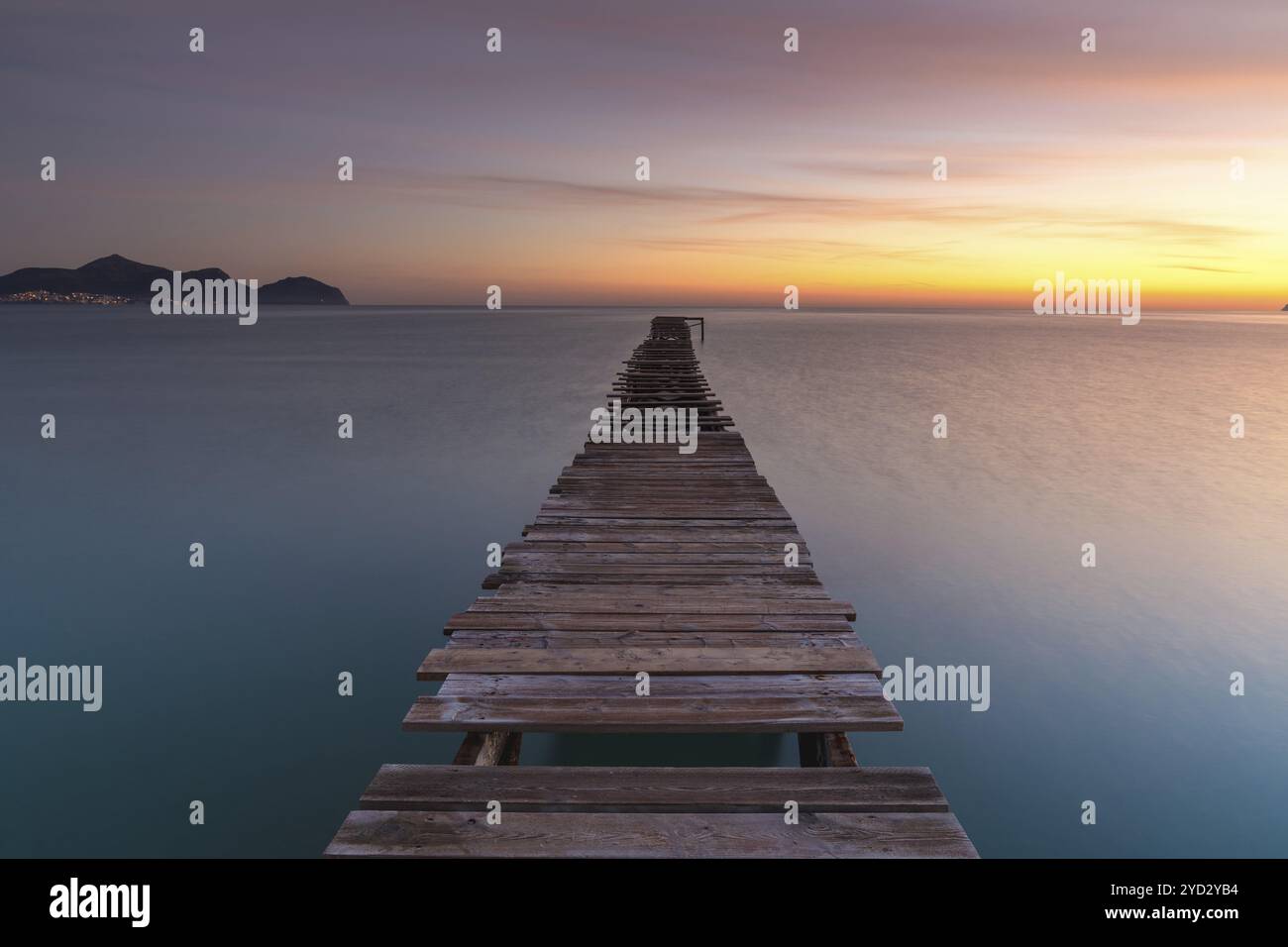 Friedliche Meereslandschaft bei Sonnenaufgang mit einem alten hölzernen Dock, der in das ruhige Meer führt Stockfoto