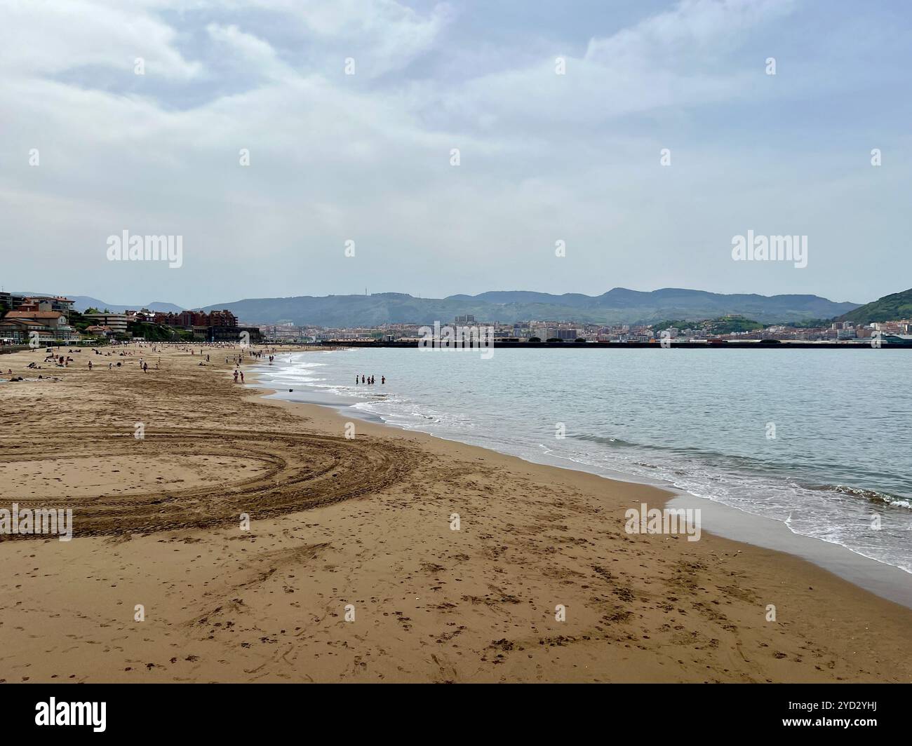 Der Strand von Getxo, Algorta, Bilao Spanien. Blick auf die Berge im Hintergrund. Nicht erkennbare Leute im Hintergrund, die am Strand liegen. Stockfoto