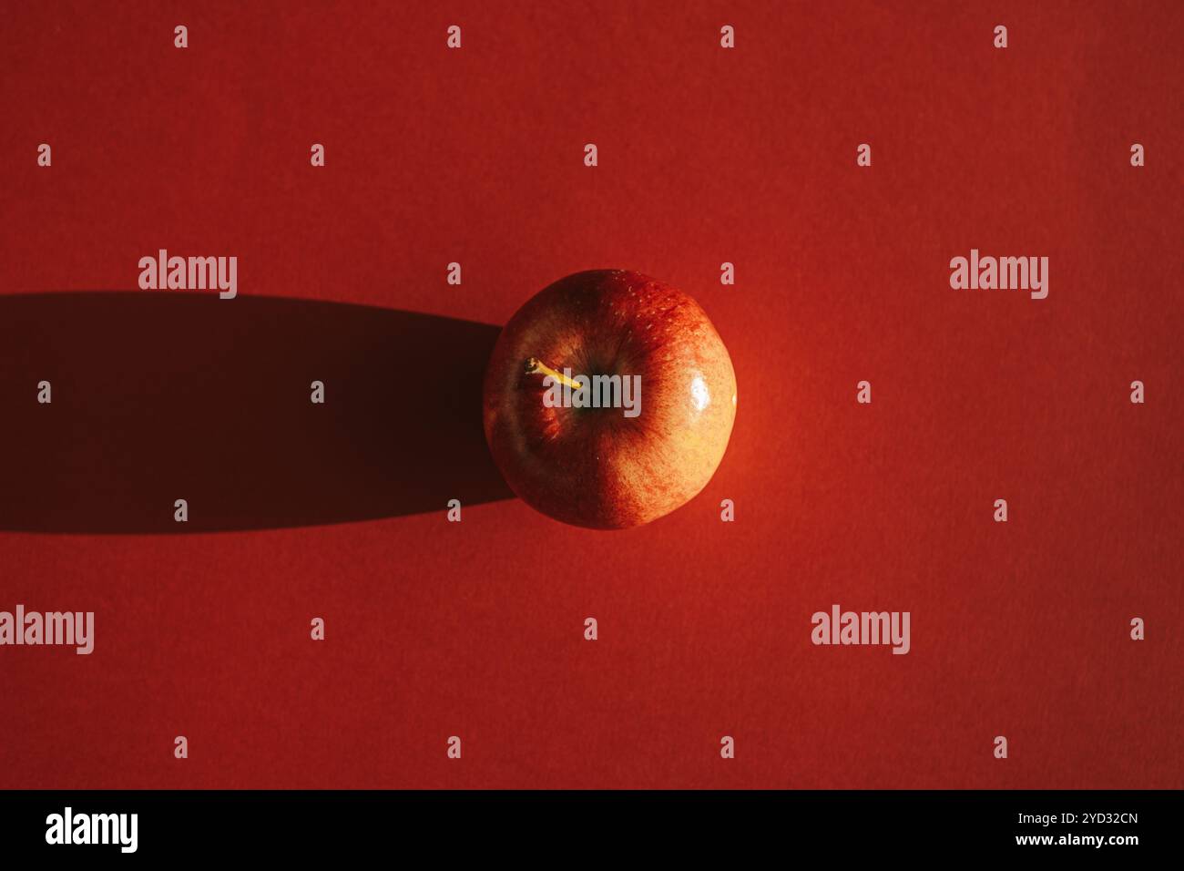 Roter Apfel bildet einen Schatten vor rotem Hintergrund Stockfoto