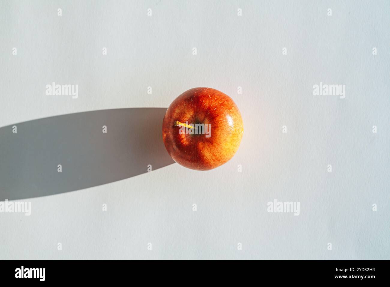 Roter Apfel, der einen Schatten vor weißem Hintergrund bildet Stockfoto