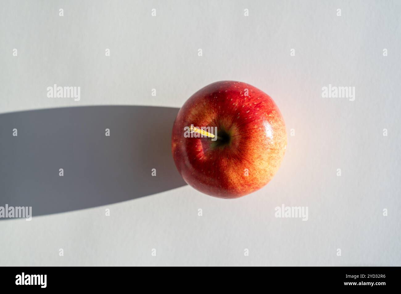 Roter Apfel, der einen Schatten vor weißem Hintergrund bildet Stockfoto