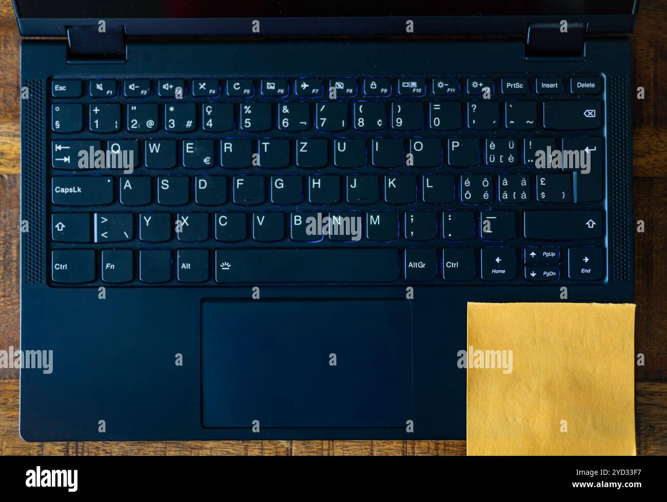 Eine Laptop-Tastatur mit einem gelben Haftnotiz auf der Unterseite. Stockfoto