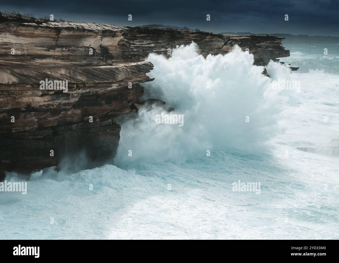 Große Wellen schlagen gegen die Klippenküste von Sydney und erzeugen große Wasserspritzen, die nach oben zu den Spitzen dieser Klippen um 30 Meter i gedrückt werden Stockfoto