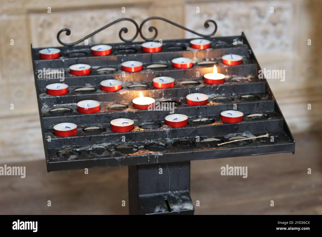 Votivstand in einer Kirche, gefüllt mit kleinen roten Kerzen Stockfoto