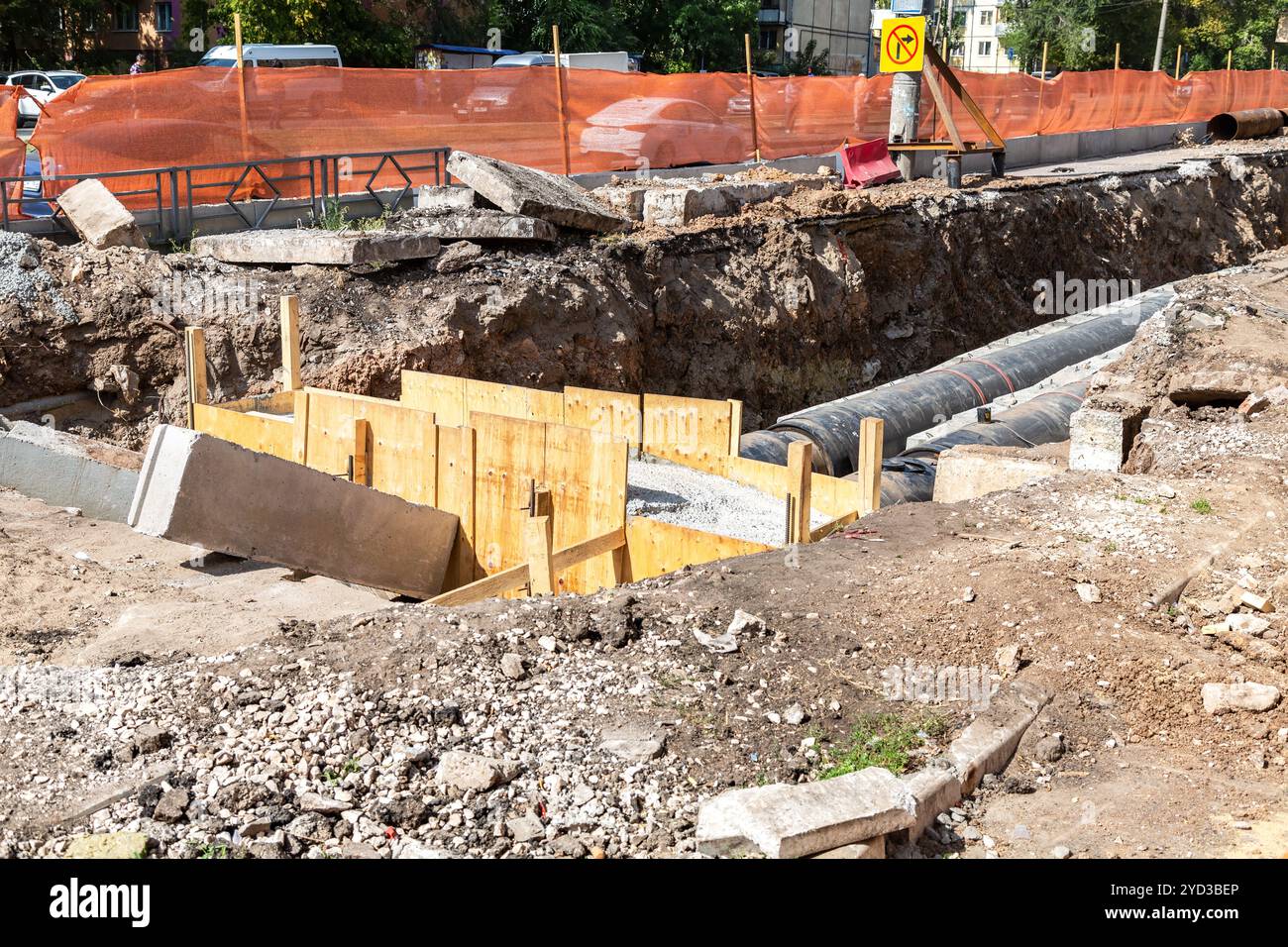 Die Bauarbeiten auf großen Eisen Rohre in einer Tiefe von ausgehobenen Grabens Stockfoto