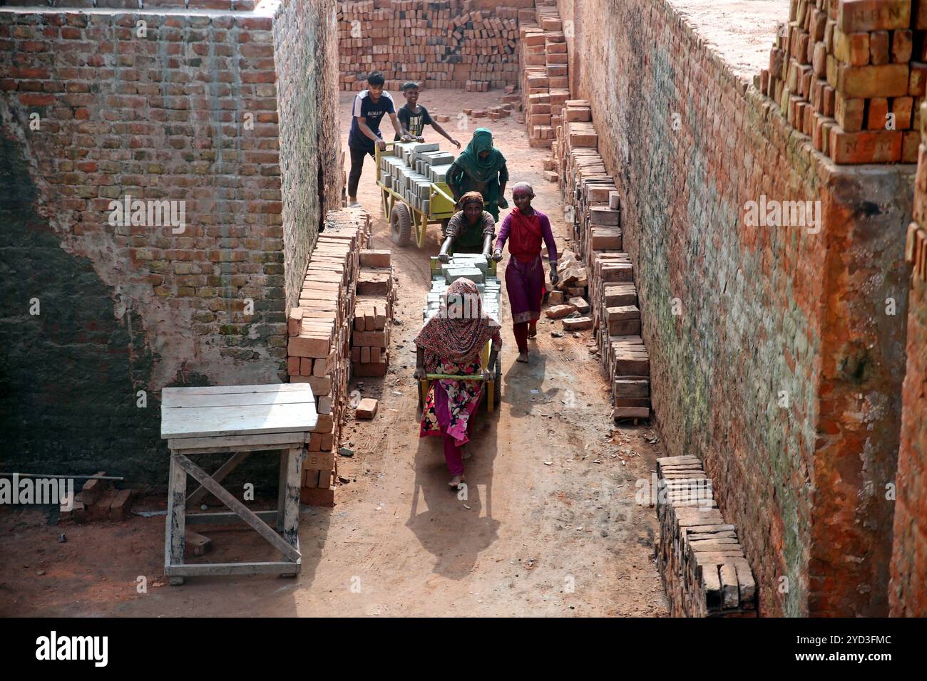 Arbeiter, die am 25. Oktober 2024 in einem Ziegelfeld in Dhaka, Bangladesch, arbeiteten. Diese Arbeiter, die unter der brennenden heißen tropischen Sonne arbeiten, leisten unter den gefährlichsten Bedingungen rückbrechende und anstrengende Arbeit. Im Alter von Teenagern bis Großeltern arbeiten sie lange Zeit, um Millionen von Ziegeln abzubauen, um einen Bauboom anzuheizen, der keine Anzeichen für ein Absinken zeigt. Die Städte Bangladeschs, eines der am dichtesten besiedelten Länder der Welt, wachsen schnell, und es besteht ein nie endender Bedarf an billigen Baumaterialien. Foto: Habibur Rahman/ABACAPRESS. KOM Stockfoto