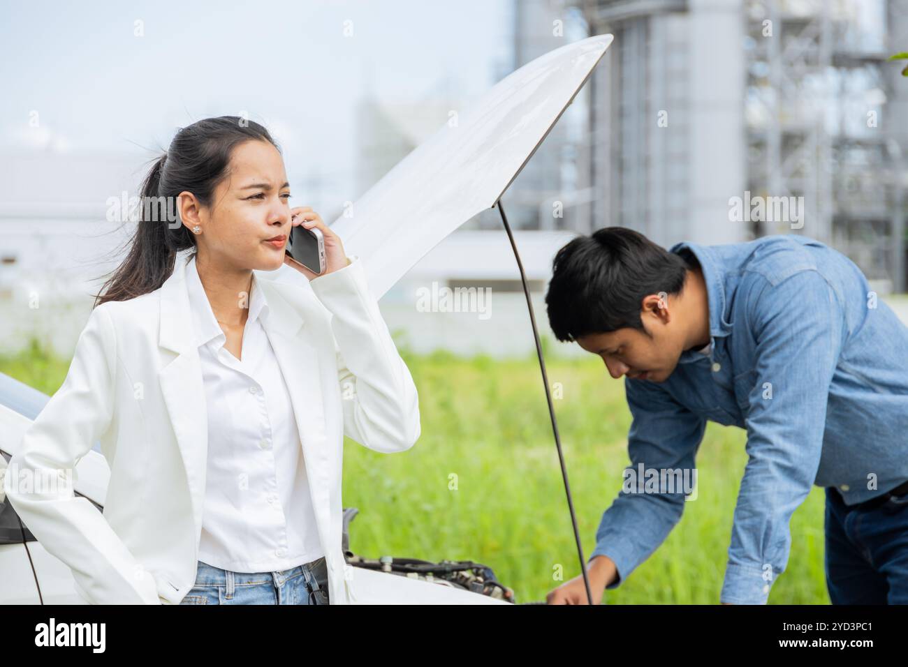 Frauenwagen auf der Straße kaputt. Ein junges Paar, das den Motor auf einer malerischen Straße überprüft Stockfoto