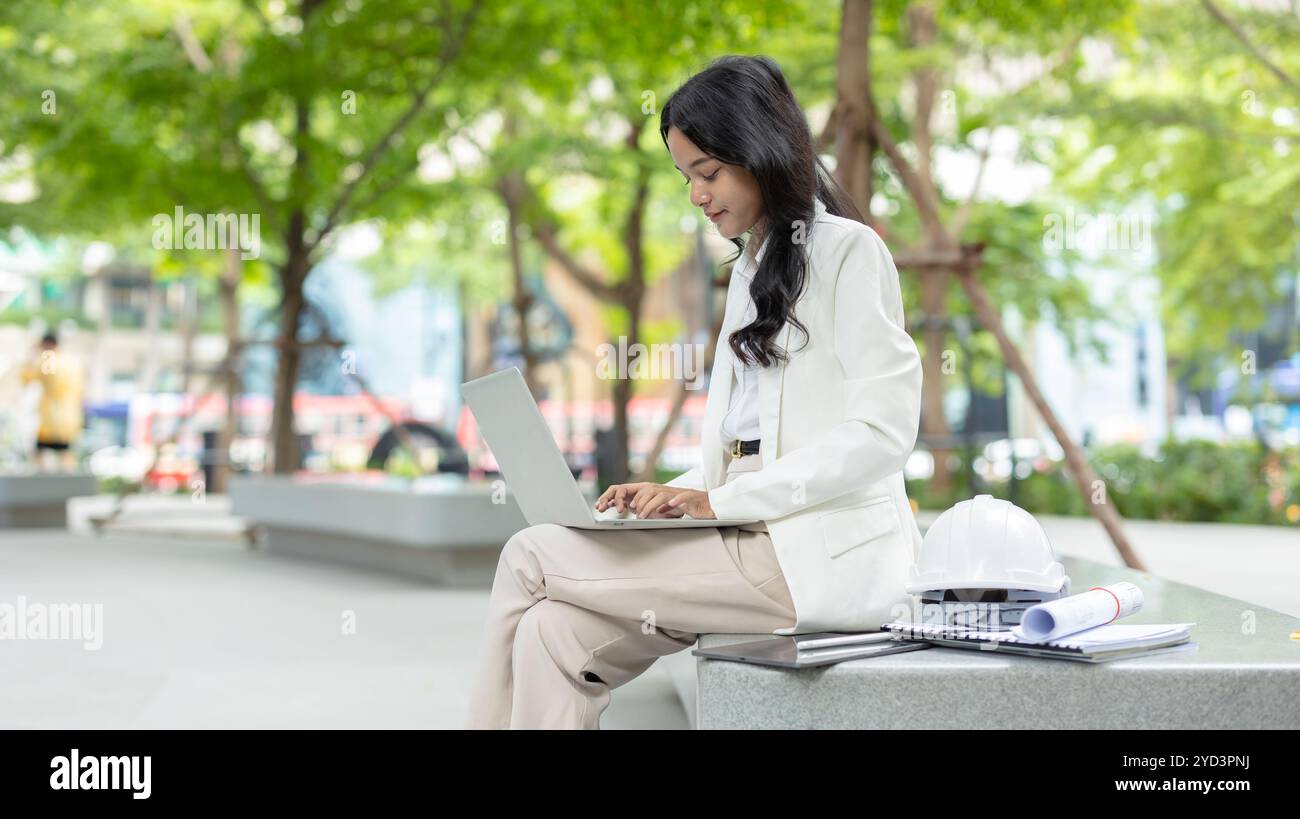 Geschäftsleute tippen an der Tastatur des Laptops. Geschäftsfrauen arbeiten im Freien mit grünem Stadthintergrund. Stockfoto