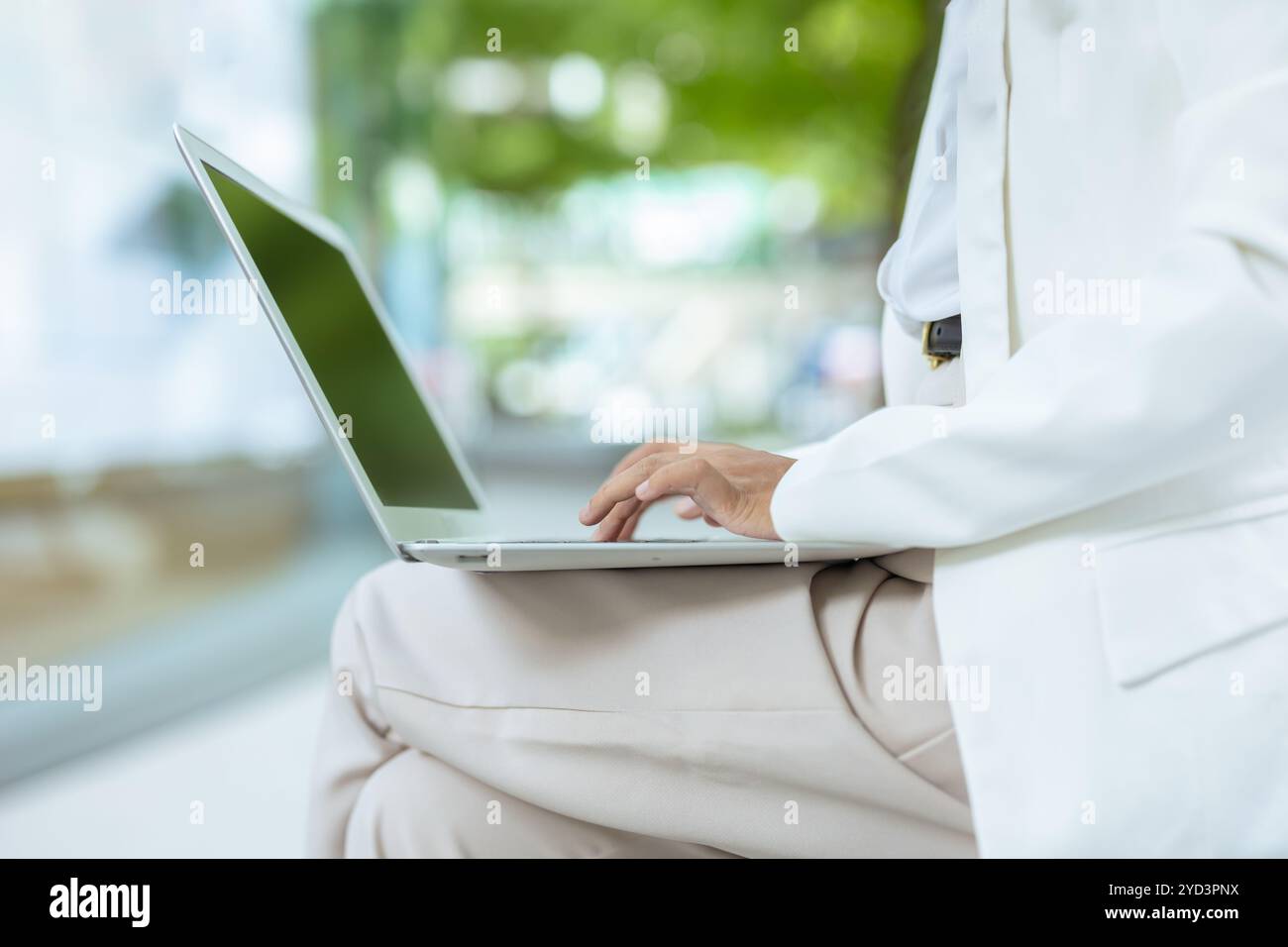 Geschäftsleute tippen an der Tastatur des Laptops. Geschäftsfrauen arbeiten im Freien mit grünem Stadthintergrund. Stockfoto