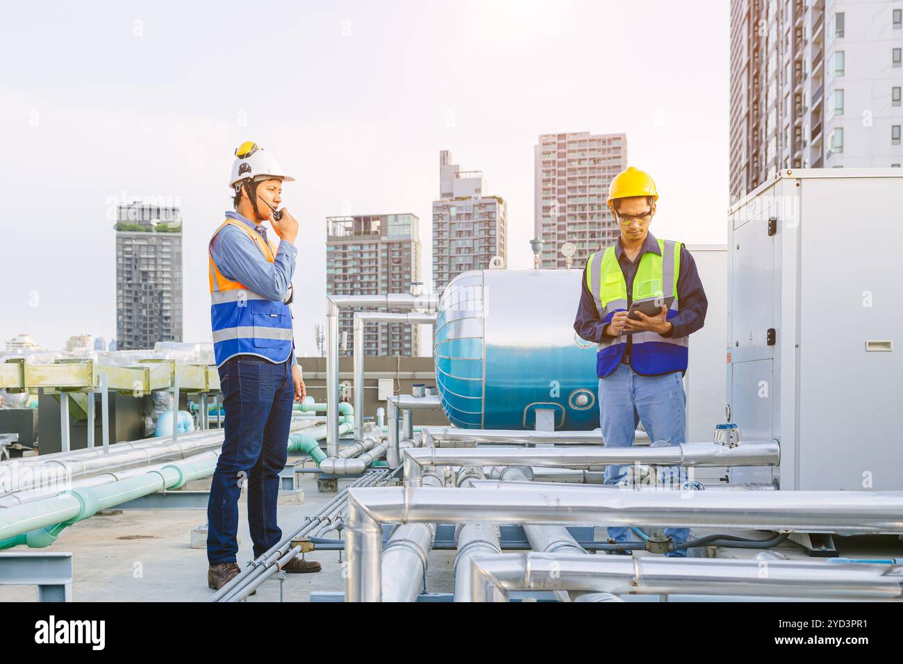 Team aus HVAC-Ingenieur, der auf dem Kesseldach arbeitet, Ingenieur, der im Dampfdampf von Gasrohrkesseln des Fabrikgebäudes arbeitet. Arbeiten im Kesselantriebsbolzen Stockfoto