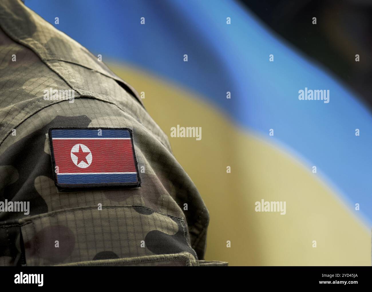 Flagge Nordkoreas auf Militäruniform und Flagge der Ukraine im Hintergrund. Nordkorea vs. Ukraine. Stockfoto