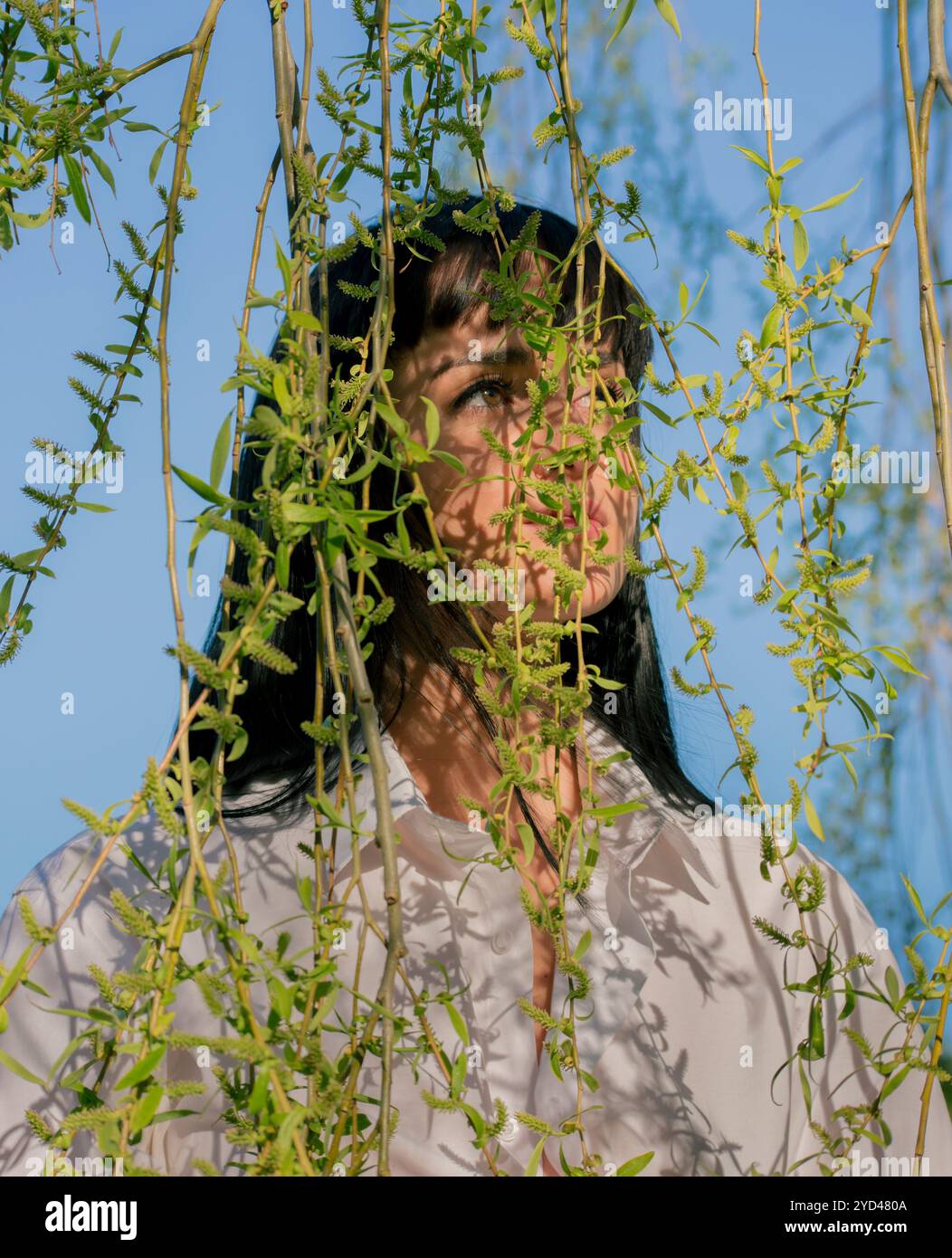Frau, die hinter grüne Blätter schaut Stockfoto