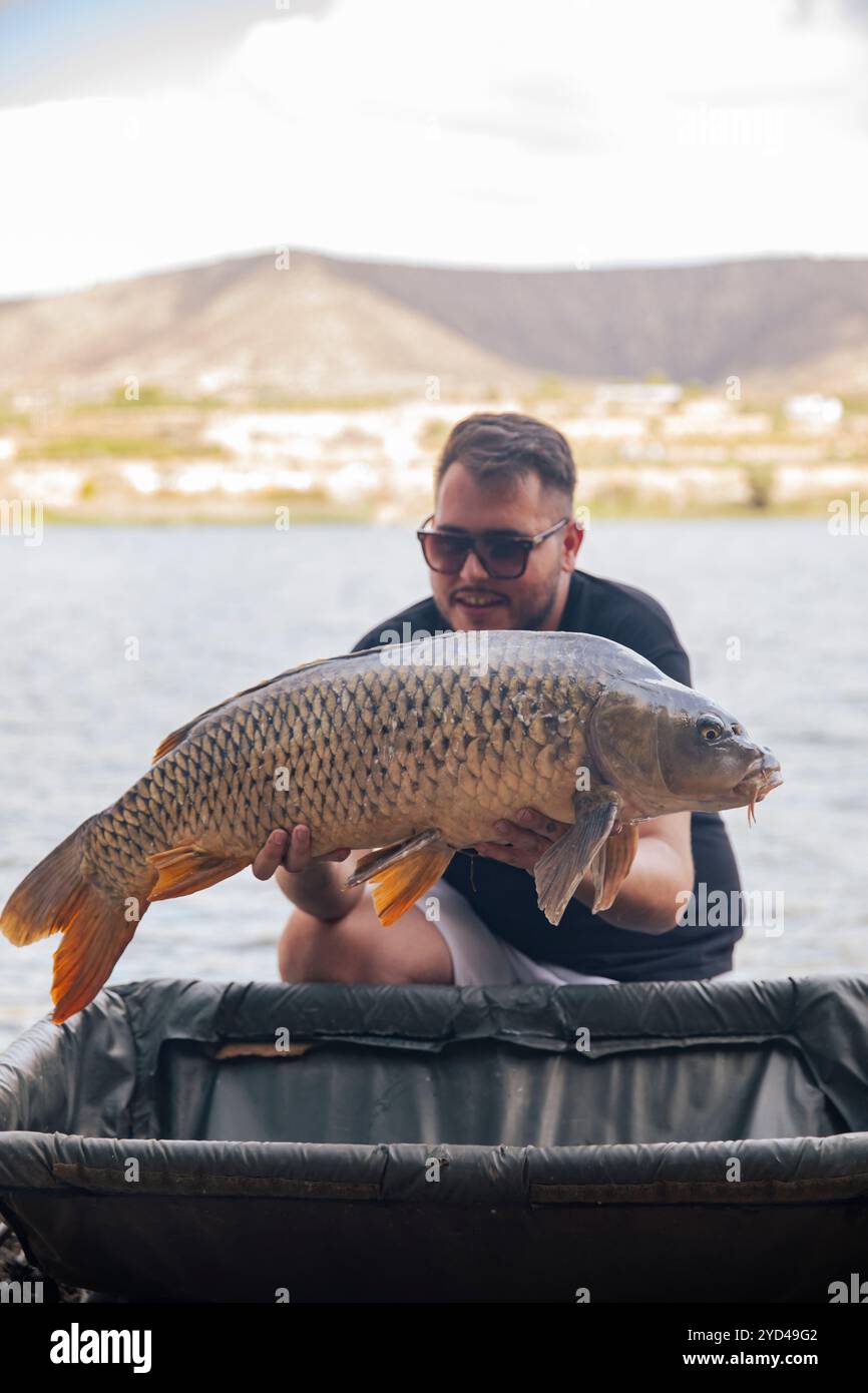 Ein kleiner Junge, der einen Karpfen zeigt, den er gerade gefangen hat Stockfoto