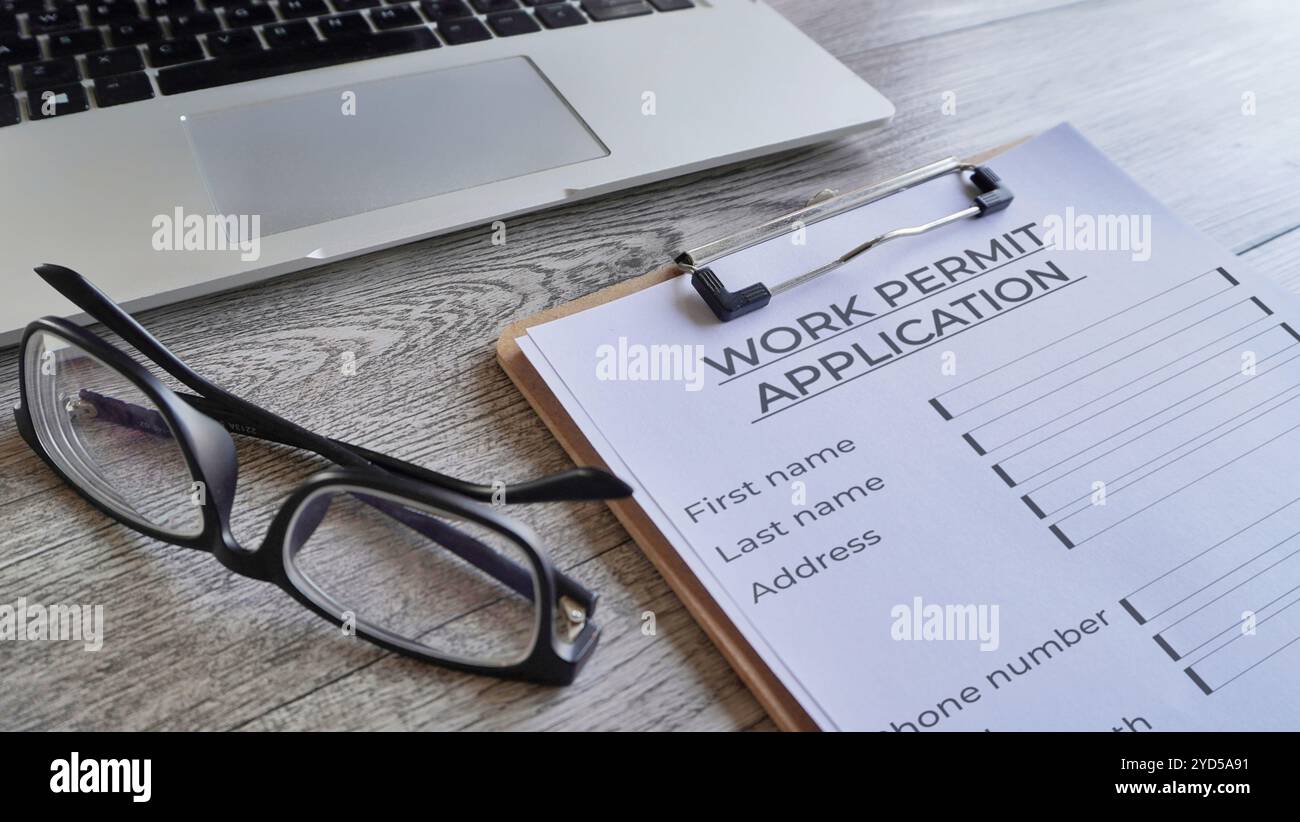 Nahaufnahme der Zwischenablage aus Papier mit dem Formular für den Antrag auf Arbeitserlaubnis auf Holztisch. Stockfoto