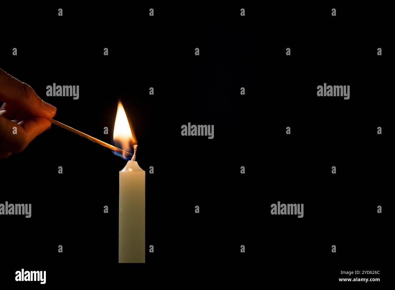 Männliche Hand zündet eine weiße Kerze mit einem Streichholz an, auf schwarzem Hintergrund, Nahaufnahme. Gedächtnis-, Symbol-, Religion- und Gebetskonzepte. Stockfoto