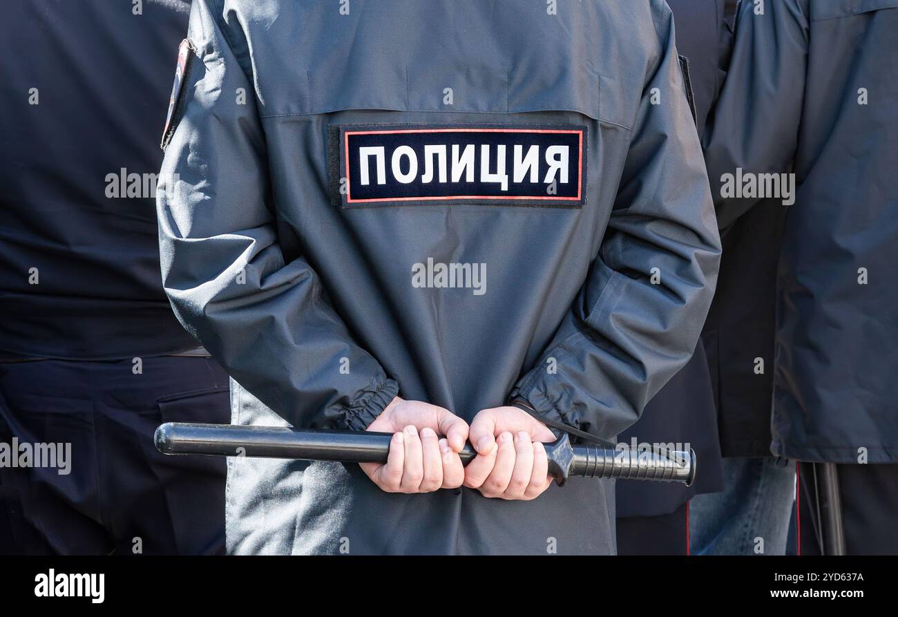 Russischer Polizist in Uniform mit Inschrift Polizei und Schlagstock Stockfoto