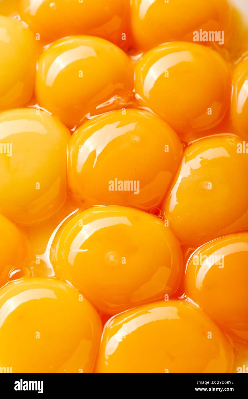 Nahaufnahme mehrerer großer Eigelbe. Die Eier sind so angeordnet, dass sie ein Gefühl von Tiefe und Textur erzeugen, mit einigen Eiern überla Stockfoto