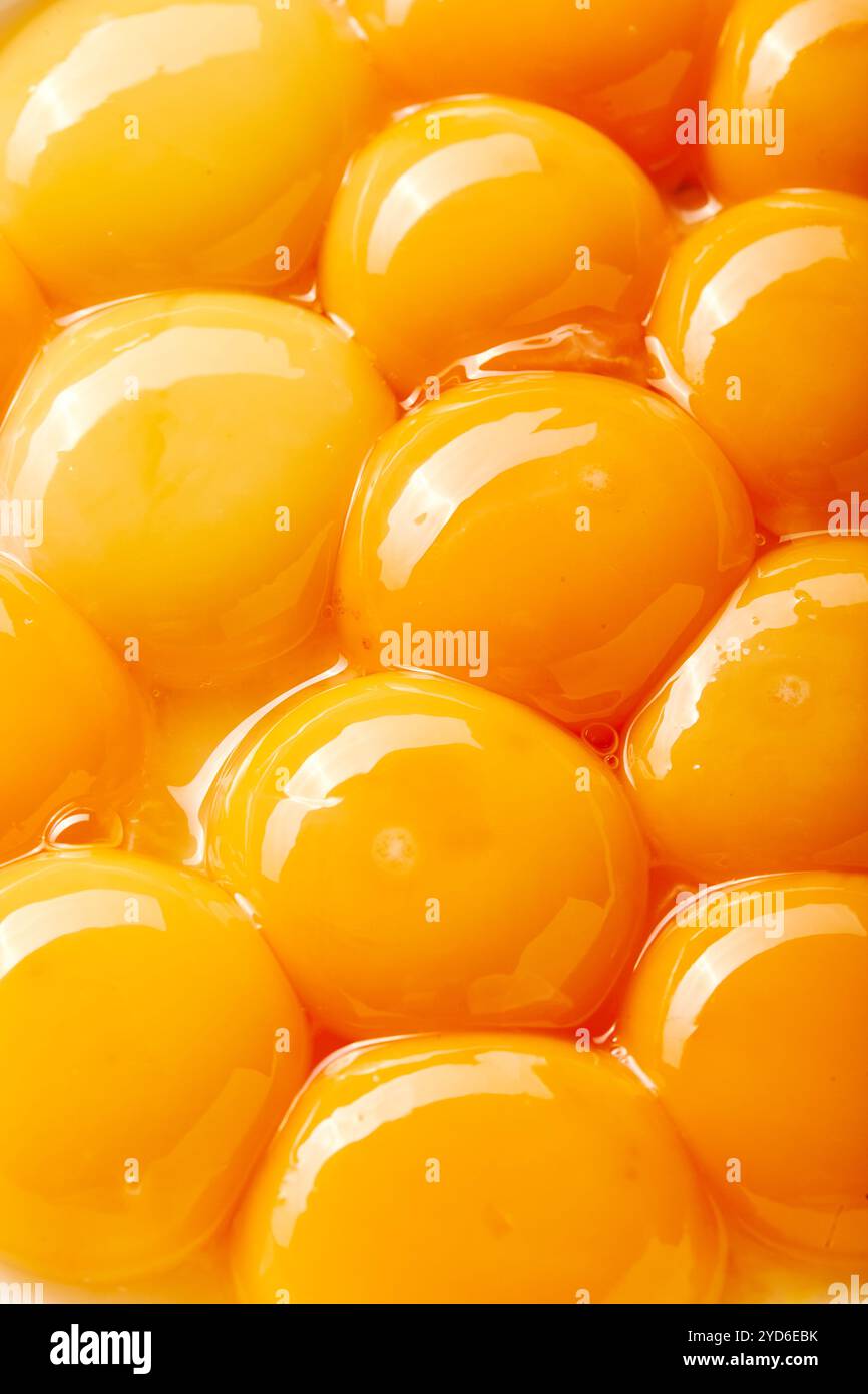 Nahaufnahme mehrerer großer Eigelbe. Die Eier sind so angeordnet, dass sie ein Gefühl von Tiefe und Textur erzeugen, mit einigen Eiern überla Stockfoto