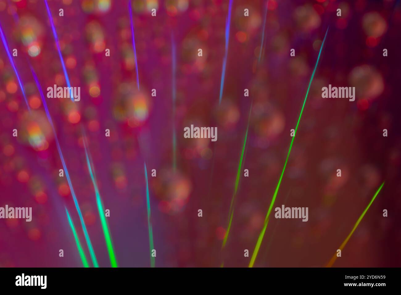 Dieses Makrofoto erfasst eine beeindruckende Reihe diagonaler Lichtstreifen in leuchtenden Grün- und Violetttönen Stockfoto