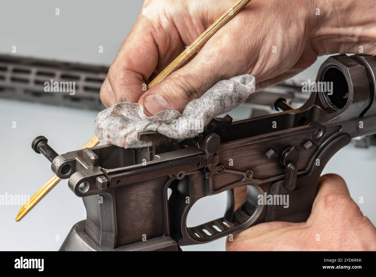 Die Hände des Mannes halten die Details der Gewehrteile und reinigen die Waffe Stockfoto