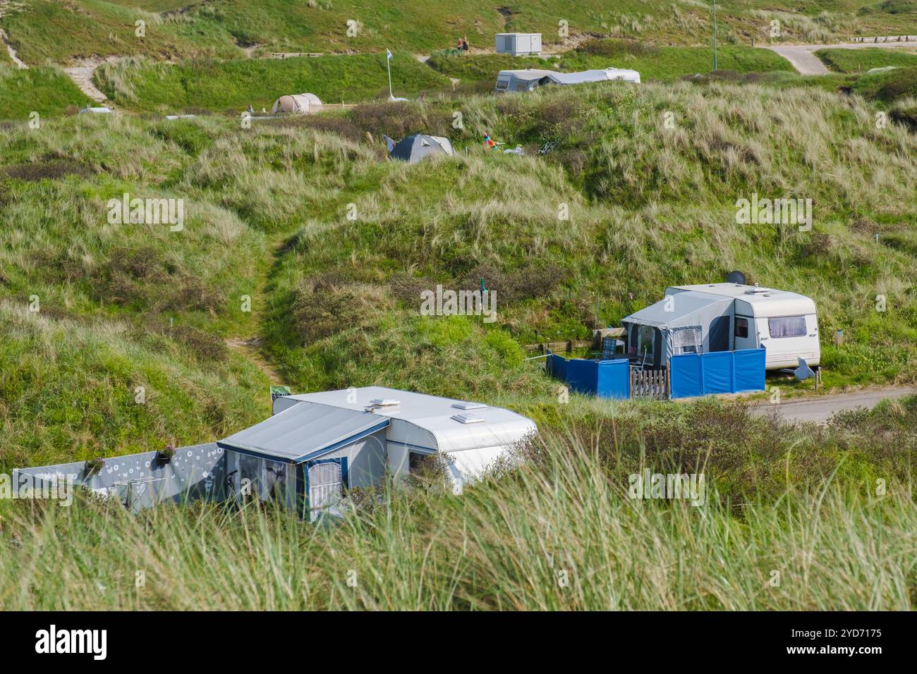 Eine ruhige Szene, in der eine Gruppe von Wohnmobil friedlich auf einem grasbewachsenen Hügel in Texel, Niederlande, parkt und sich harmonisch mit ihr verbindet Stockfoto