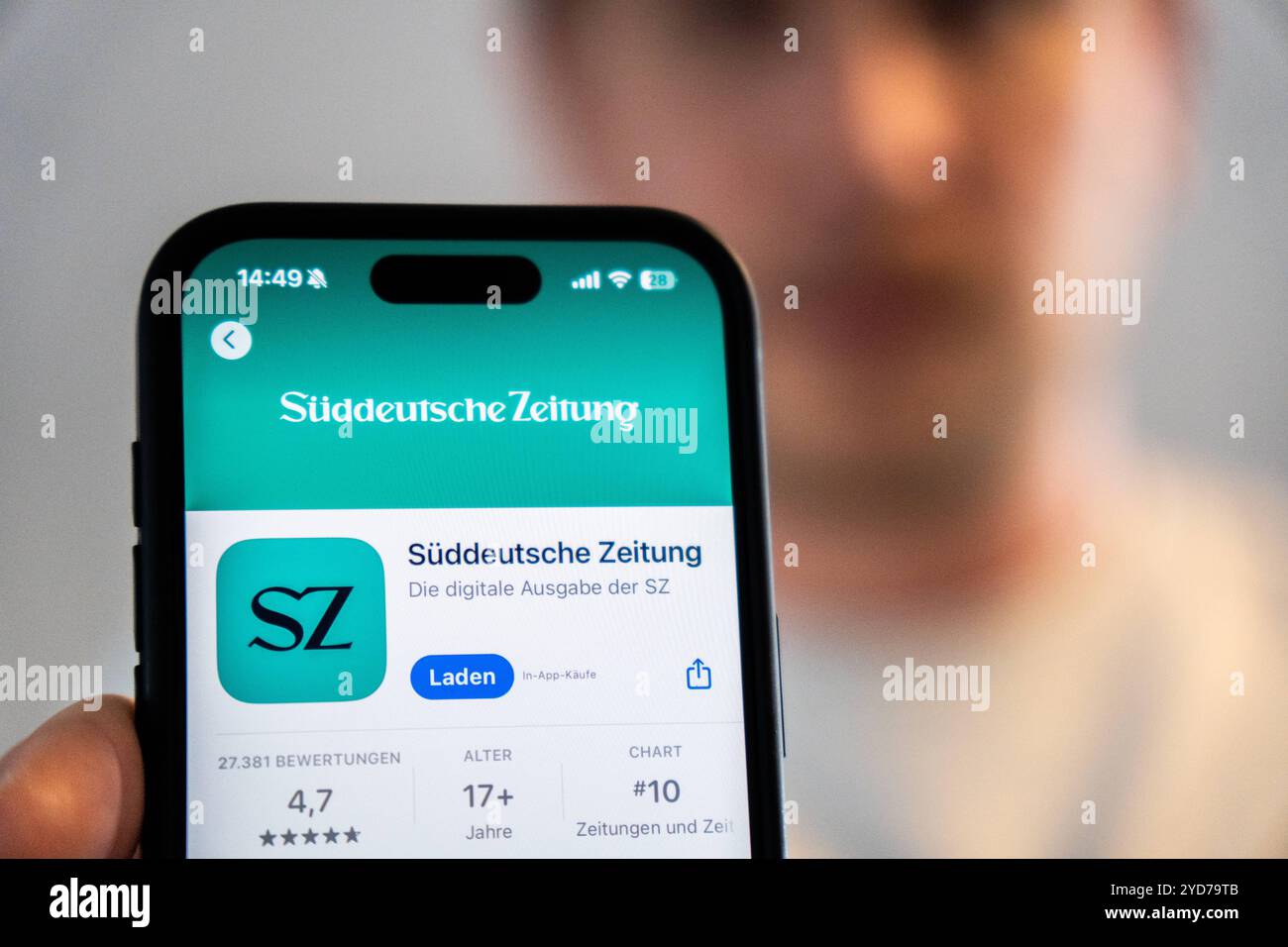 Bayern, Deutschland - 25. Oktober 2024: Ein Mann hält ein iPhone mit der App Süddeutsche Zeitung SZ im Appstore. Symbolisches Bild Einstellung lokaler Druckausgaben und Schließung lokaler Redaktionen *** ein Mann hält ein iPhone mit der App Süddeutsche Zeitung SZ im Appstore. Symbolbild Einstellung der lokalen Printausgaben und schließung der Lokalredaktionen Stockfoto