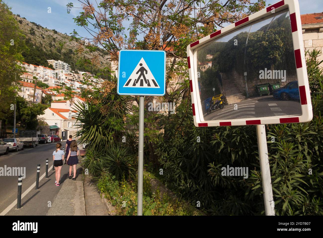 Nachdem wir gerade die Straße überquert haben, gehen Familie mit Kindern/Kindern von einem 'Zebraüberquerung' und einem Weitwinkelspiegel, einer Übergangshilfe, nahe einer scharfen Kurve weg. Dubrovnik. Kroatien. (138) Stockfoto