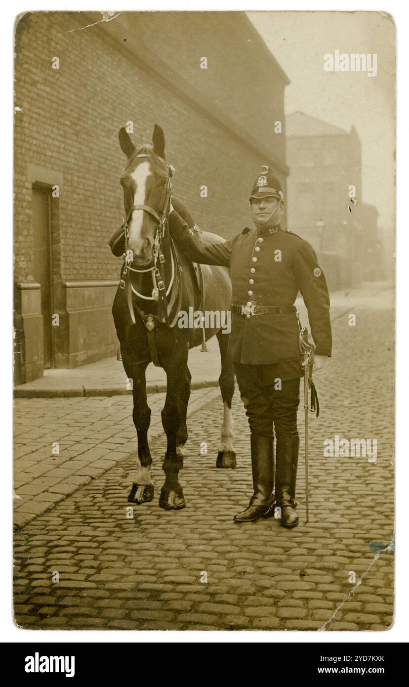 Ursprünglich aus den frühen 1900er Jahren stammende Postkarte eines Polizisten in Uniform, der stolz neben seinem Pferd stand, Großbritannien um 1910 Stockfoto