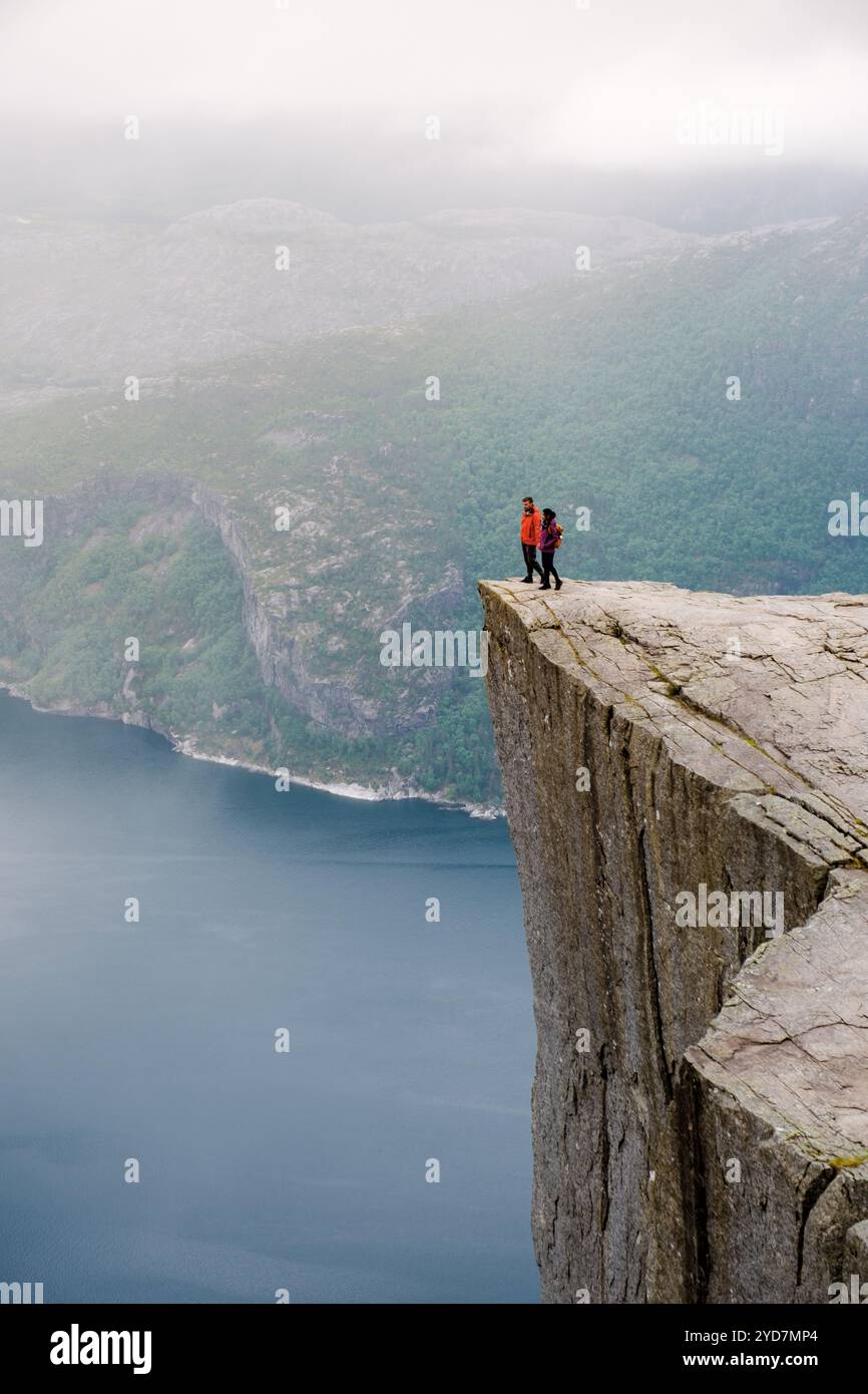 Preikestolen, Norwegen, zwei Menschen stehen am Rande einer Klippe mit Blick auf einen Fjord in Norwegen. Die Klippe ist bekannt als Preikestolen oder Kanzel Rock, und ich Stockfoto