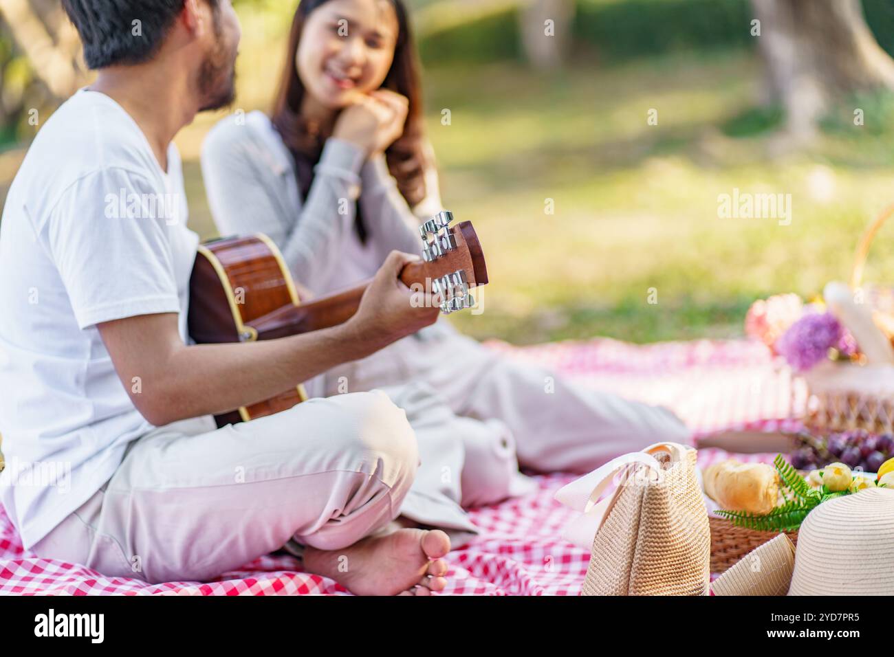 Verliebtes Paar genießt Picknickzeit beim Gitarrenspielen im Park Picknick im Freien. Glückliches Paar, das togetherÂ mit Picknickkorb entspannt Stockfoto