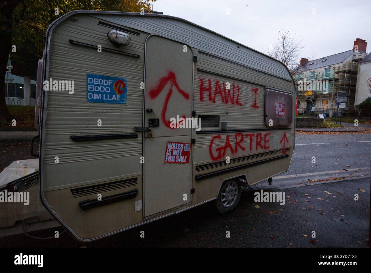 Carmarthen, Großbritannien. 25. Oktober 2024. Eine Karawane wird vor den walisischen Regierungsbüros in Carmarthen verlassen, die mit Graffiti befüllt ist, die die Menschen zum Recht auf Wohnung auffordern, nachdem die walisische Regierung vermeintlich nicht aktiv war. Gruffydd Thomas/Alamy Stockfoto