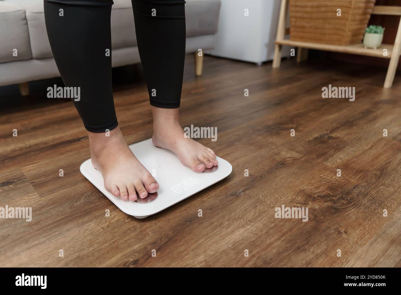 Fettdiät und Schuppenfüße stehen auf elektronischen Waagen zur Gewichtskontrolle. Messgerät in Kilogramm für eine Diätkontrolle. Stockfoto