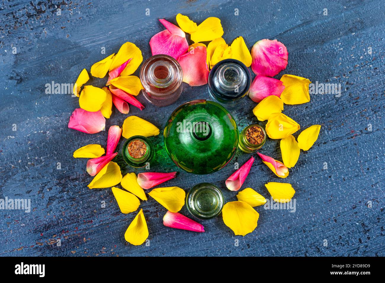 Flaschen mit ätherischen Ölen umgeben von Rosenblättern. Stockfoto