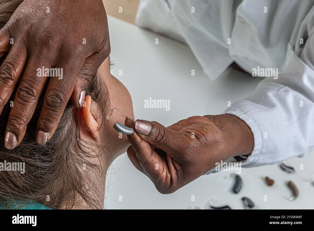 Hörgeräteexperte, die ein Hörgerät anprobieren. Stockfoto