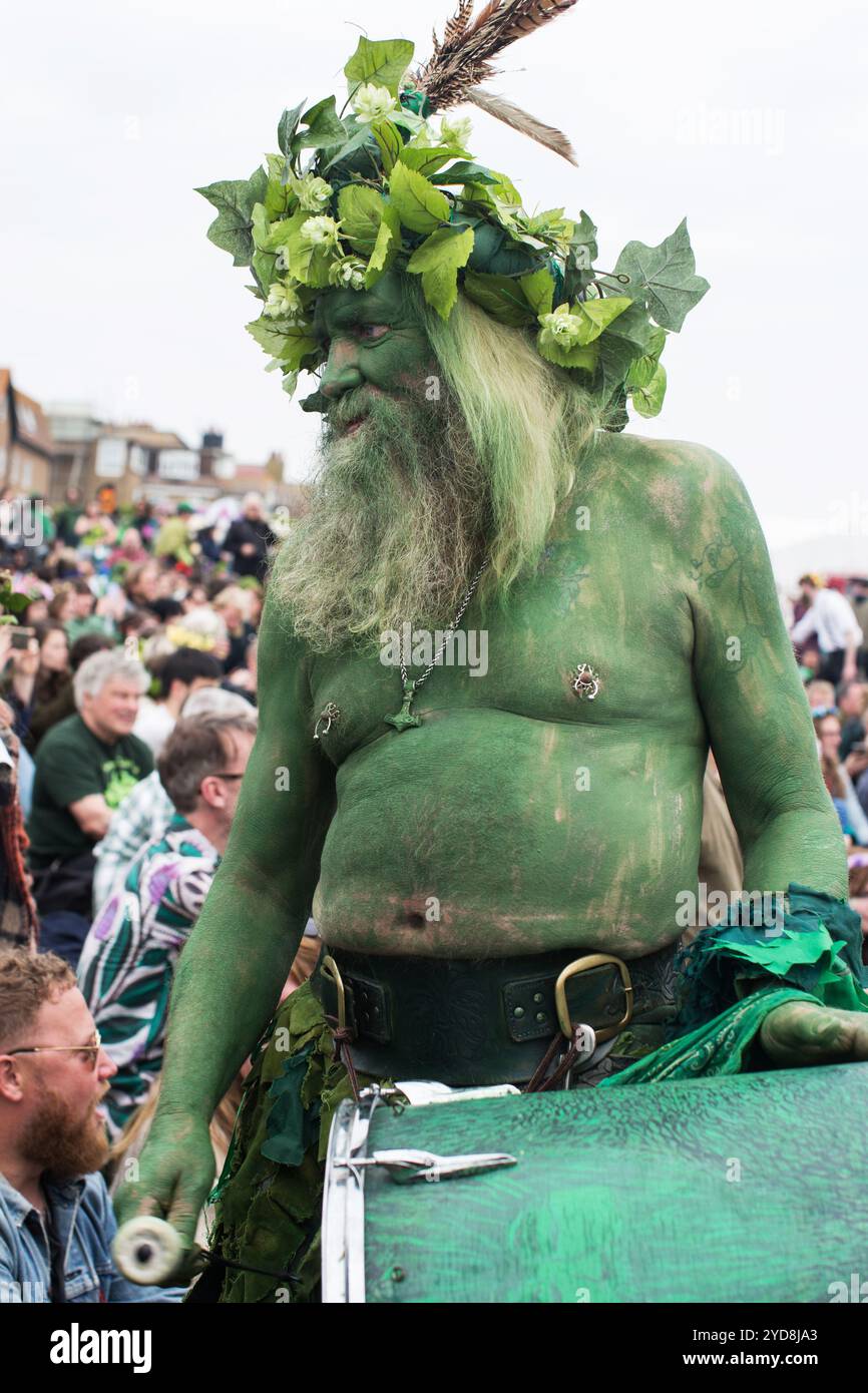 Grüner Mann, der beim Jack in the Green Festival trommelt, grün bemalt, mit Efeu und Blättern geschmückt, feiert englische Folklore und Frühlingstraditionen. Stockfoto