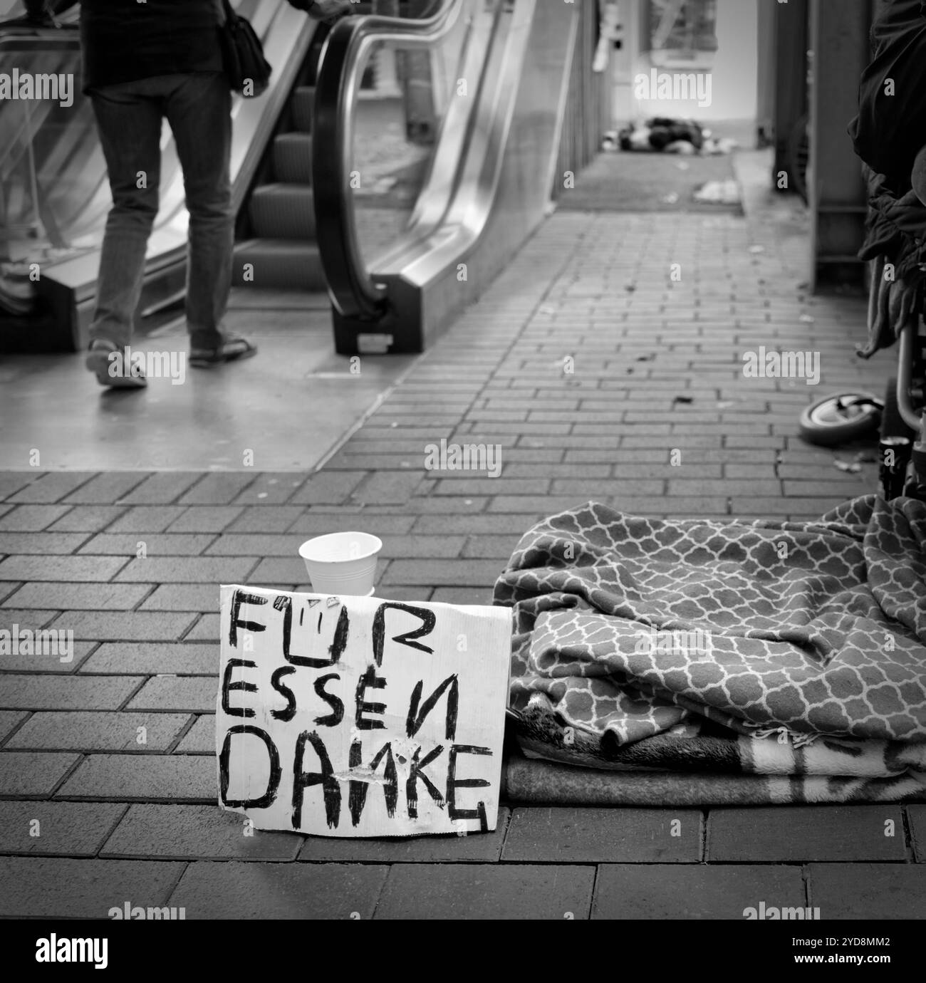 Pappschild mit der Aufschrift „für Essen Danke“ und eine Decke mit der Darstellung der Obdachlosigkeit in einer deutschen Stadt (s & W) Stockfoto