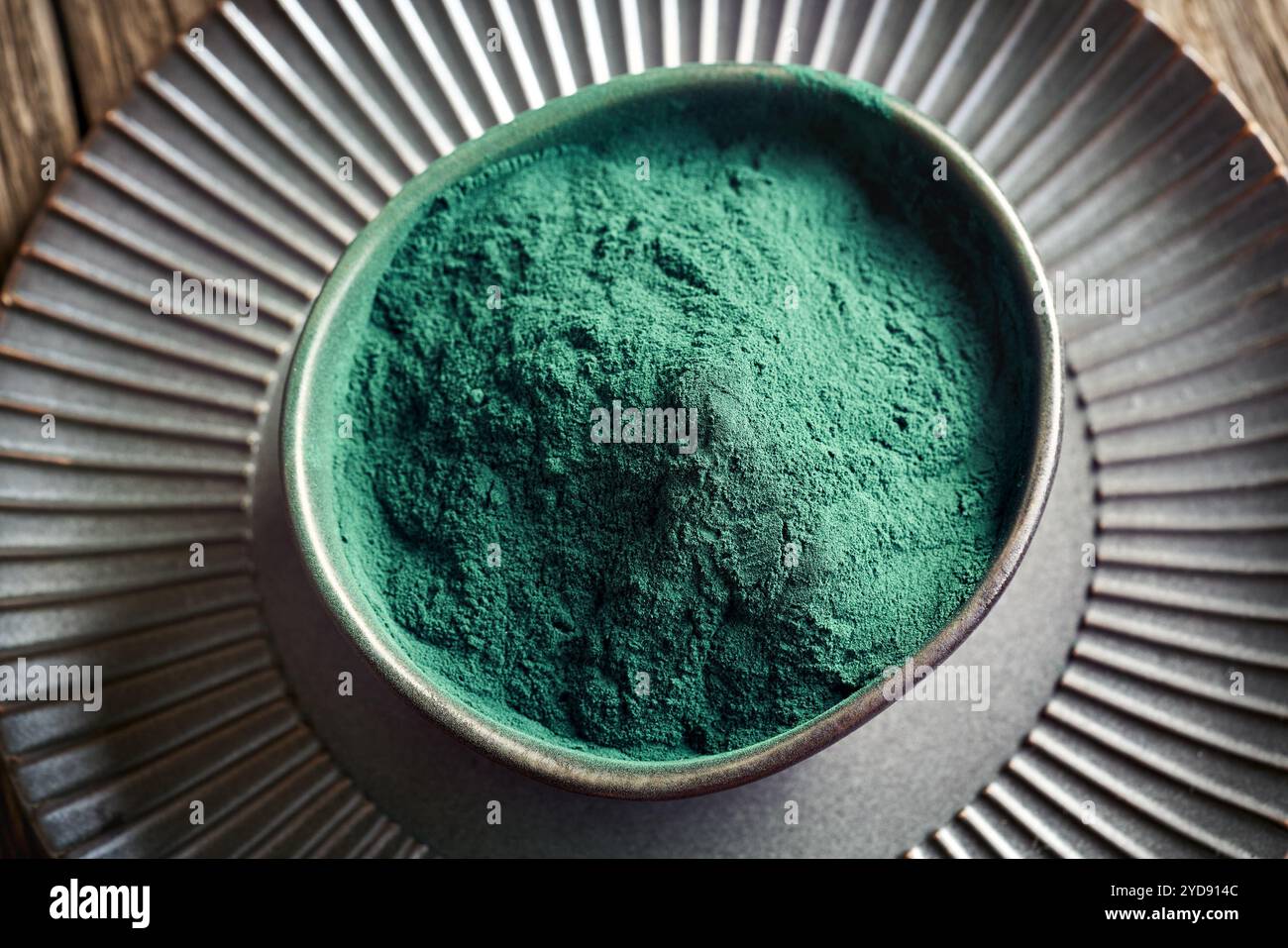 Grünes Spirulina-Pulver in einer schwarzen Schüssel auf einem Tisch Stockfoto